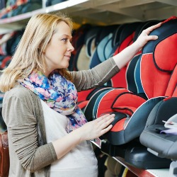 woman choosing child car seat for newborn baby in shop supermarket