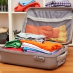 Open grey suitcase with clothing in room