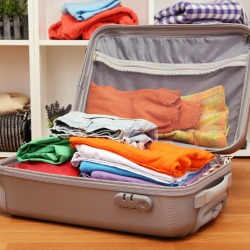 Open grey suitcase with clothing in room
