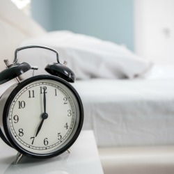 black alarm clock and bed