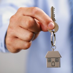Holding out house keys on a house shaped keychain