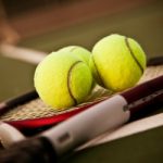 A shot of a tennis racquet and tennis balls on the tennis court