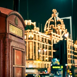 two red phone boxes at night in Knightsbridge against lit shopping centre