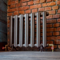 Vintage iron radiator for home with legs. Old cast iron central heating battery.