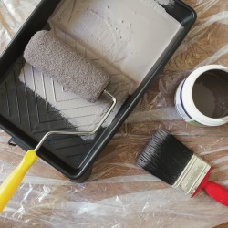 Overhead view of home painting equipment brush, roller, tray and paint pot