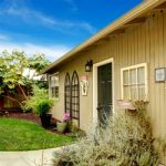 Spring backyard with flowerbed, trees and naturally matched wooden shed