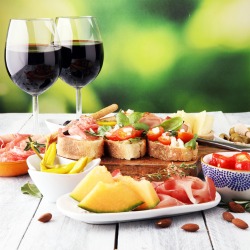 Italian antipasti wine snacks set. Cheese variety, Mediterranean olives, pickles, Prosciutto di Parma, tomatoes, artichokes and wine in glasses