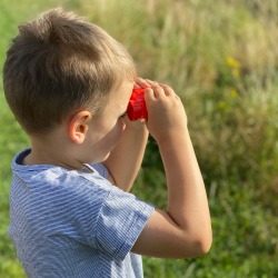 boy with binoculars looking over a field