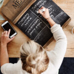 Overhead Shot Looking Down On Woman At Home Writing Meal Plan